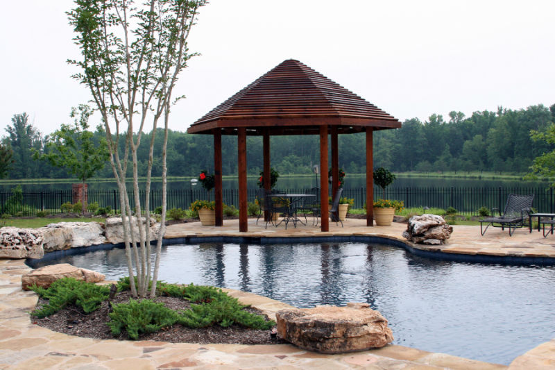 A custom shaped pool with wood arbor gazebo.