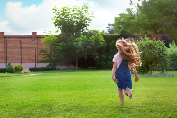 Young girl running on a manicured lawn.